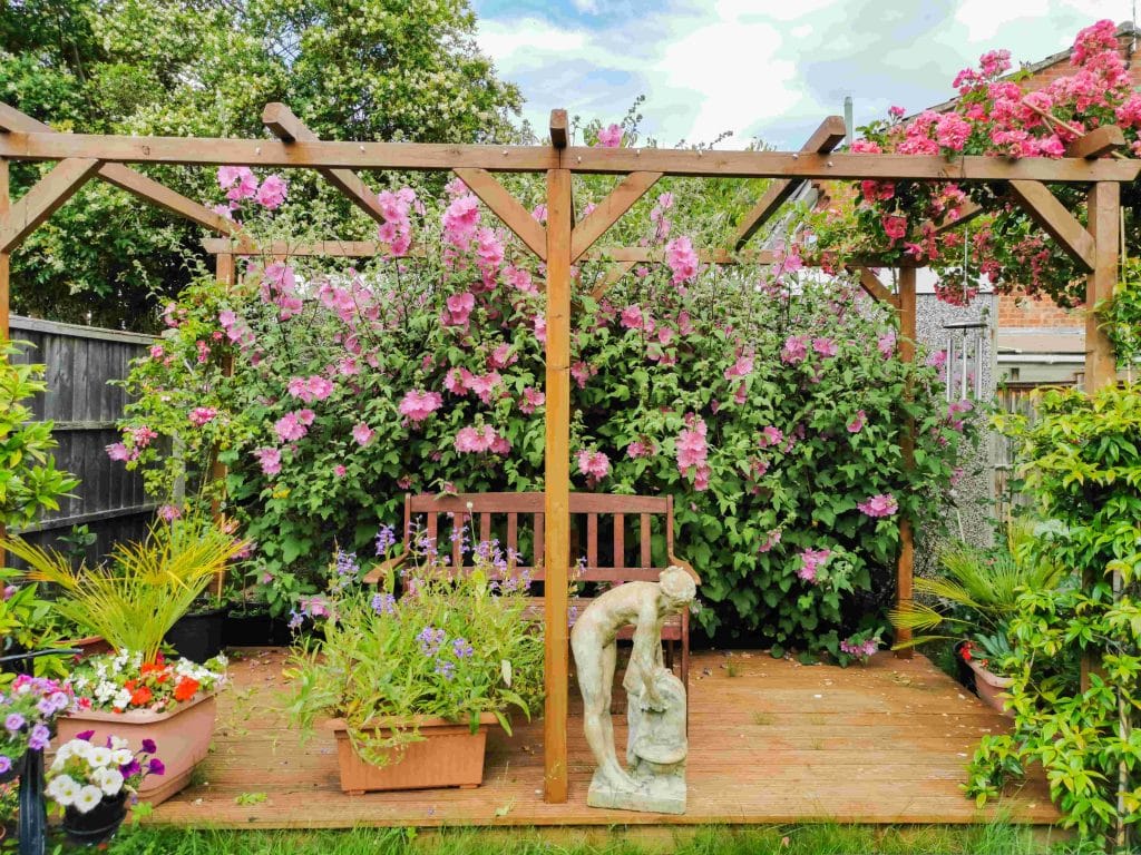 Drewniana pergola ogrodowa, kolorowe rośliny, zieleń, rzeźba